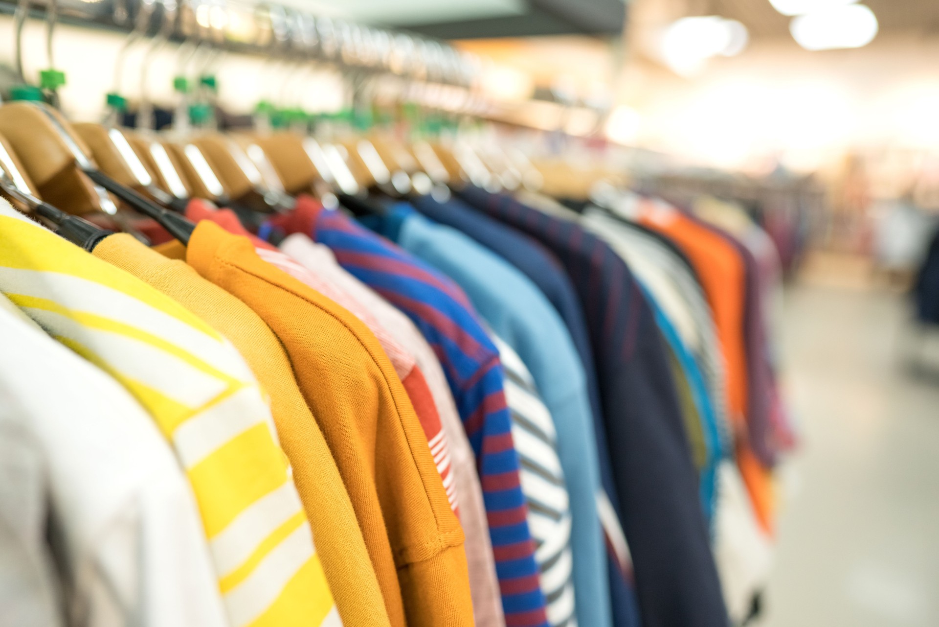 Clothes on hangers - new fashion collection at fashionable clothes store. Clothing rental or secondhand store concept. Clothes stall against blurred store background with copy space